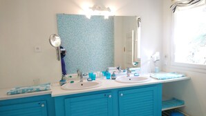 A bathroom with two sinks, a mirror, and a window.