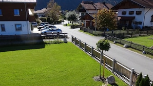 Eine Wohnstraße mit Häusern, parkenden Autos und einem Berg im Hintergrund.