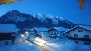 Ein verschneites Dorf mit Häusern und einem Berg im Hintergrund.