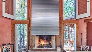 Una habitación acogedora con chimenea, paredes de madera y ventanas amplias.