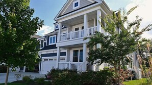 Une maison à deux étages avec un porche à l’avant, un garage et une pelouse bien entretenue.