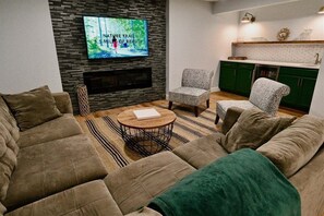 Ett modernt vardagsrum med en öppen spis, en tv och ett köksområde.