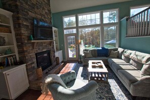 Ett vardagsrum med en öppen spis, en soffa, ett soffbord och en tv.