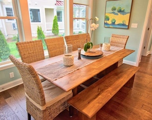 A dining area with a wooden table, wicker chairs, and a bench.