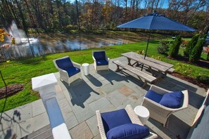An outdoor patio with wicker furniture, a wooden table, and a blue umbrella.