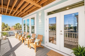 A covered outdoor seating area with wooden chairs and a white door with glass panels. - New Home Heated Pool, Game Room, 2 Min to Beach, Sleeps 18, 5BR/5.5Ba/3300 Sq Ft (North Myrtle Beach)