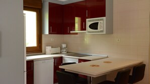 Una cucina compatta con forno a microonde, macchina del caffè e un piccolo spazio pranzo con due sedie.