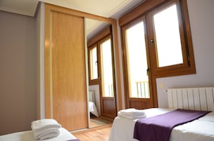 A room with a bed, a wooden wardrobe, and a window.
