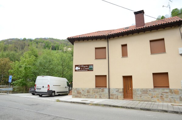 A building with a beige facade, stone base, and a tiled roof. There is a sign on the building that reads "El Rincon de Limes." - El Rincón de Limés (Cangas del Narcea)