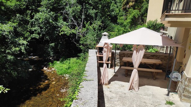 Un'area patio con pavimento in cemento, un piccolo ruscello e un tavolo e una panca in legno.