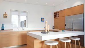 Een moderne keuken met een groot eiland, houten kastjes, een roestvrijstalen koelkast en een raam met uitzicht.