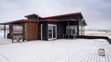 Situated on a wooden deck, this two-story building offers a serene atmosphere with large windows and doors.