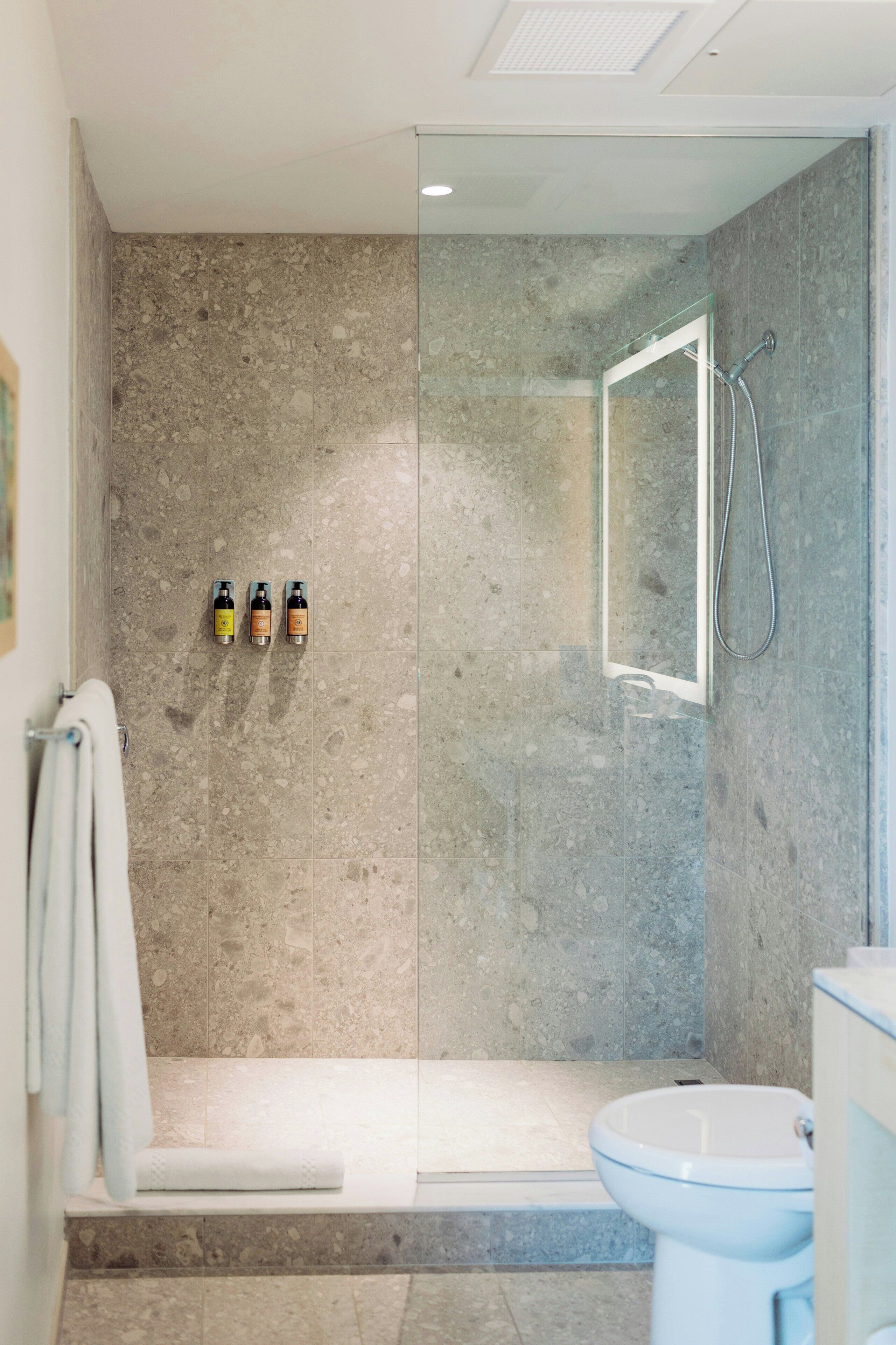 A modern bathroom with a glass-enclosed shower, a toilet, and a sink.