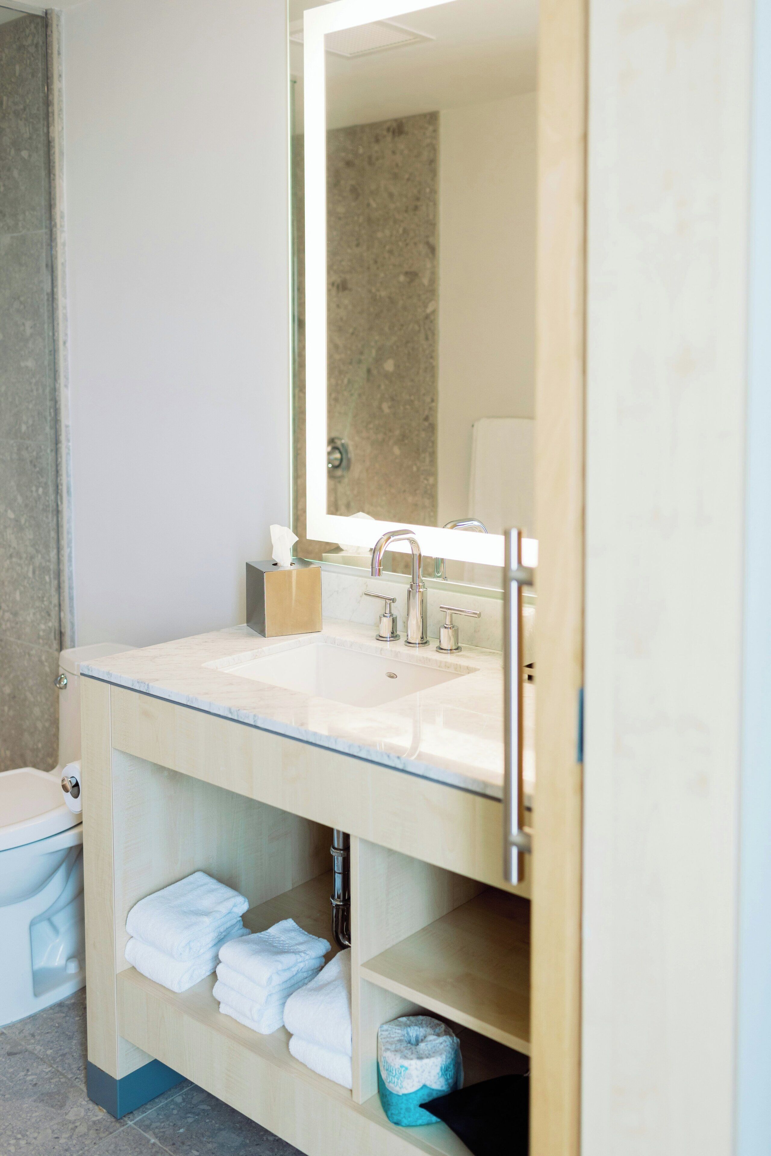 A bathroom with a white sink, a mirror, and a toilet.