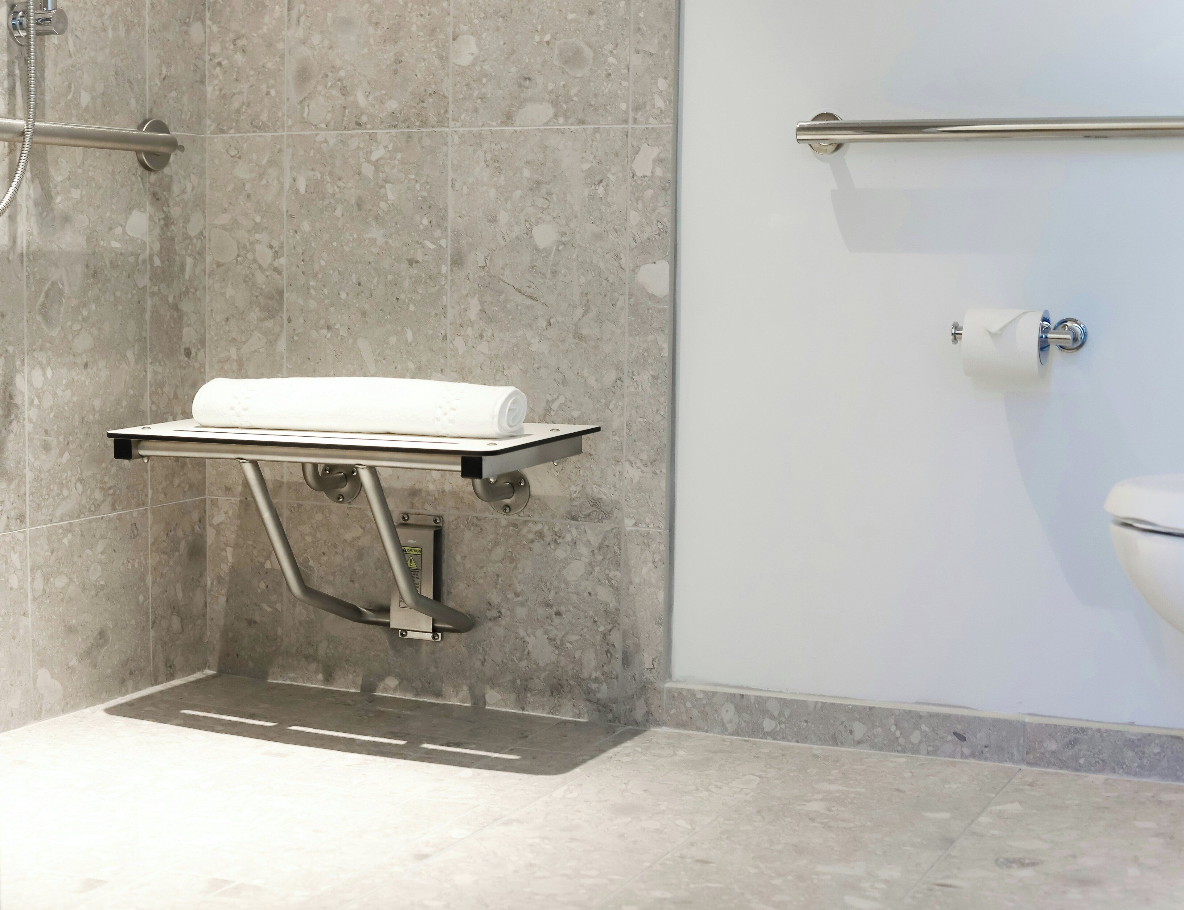 Een badkamer met een douche, toilet en handdoekhouder.