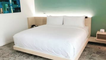 A hotel room with a bed, a nightstand, a bedside table, and a wall-mounted light.