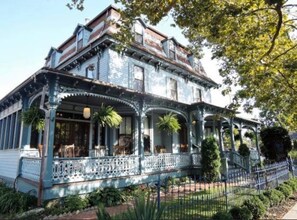 A large, historic house with a porch, multiple windows, and a well-maintained garden. - The Hugh Boutique B&B (Cape May)