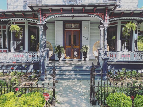 A Victorian-style house with a front porch, large windows, and a front door.