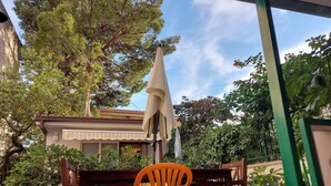 A patio area with a table and chairs, surrounded by potted plants and trees.
