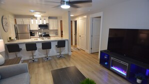 A modern kitchen with a central island, bar stools, and a flat-screen TV. - Modern Condo only Minutes from Deadwood & Sturgis! (Lead)