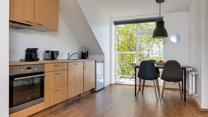 A modern kitchen with wooden cabinets, a built-in oven, a dishwasher, and a dining area with two chairs and a table.