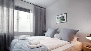 A neatly made bed with a white and gray striped bedspread, two pillows, and a folded towel on the side.