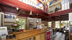 Un restaurante con piso a cuadros, mostrador de madera y un balcón con banderas.