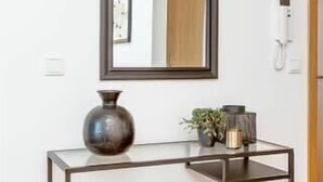 A modern console table with a mirror, a vase, and a small plant. - Tyr Downtown Studio Apartment (Reykjavík)