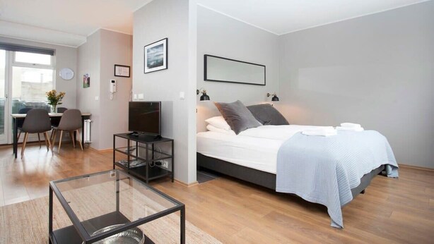 A modern bedroom with a bed, bedside tables, a desk, and a chair. - Tyr Downtown Studio Apartment (Reykjavík)