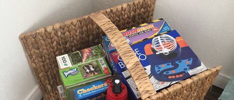 A woven basket filled with board games and toys.