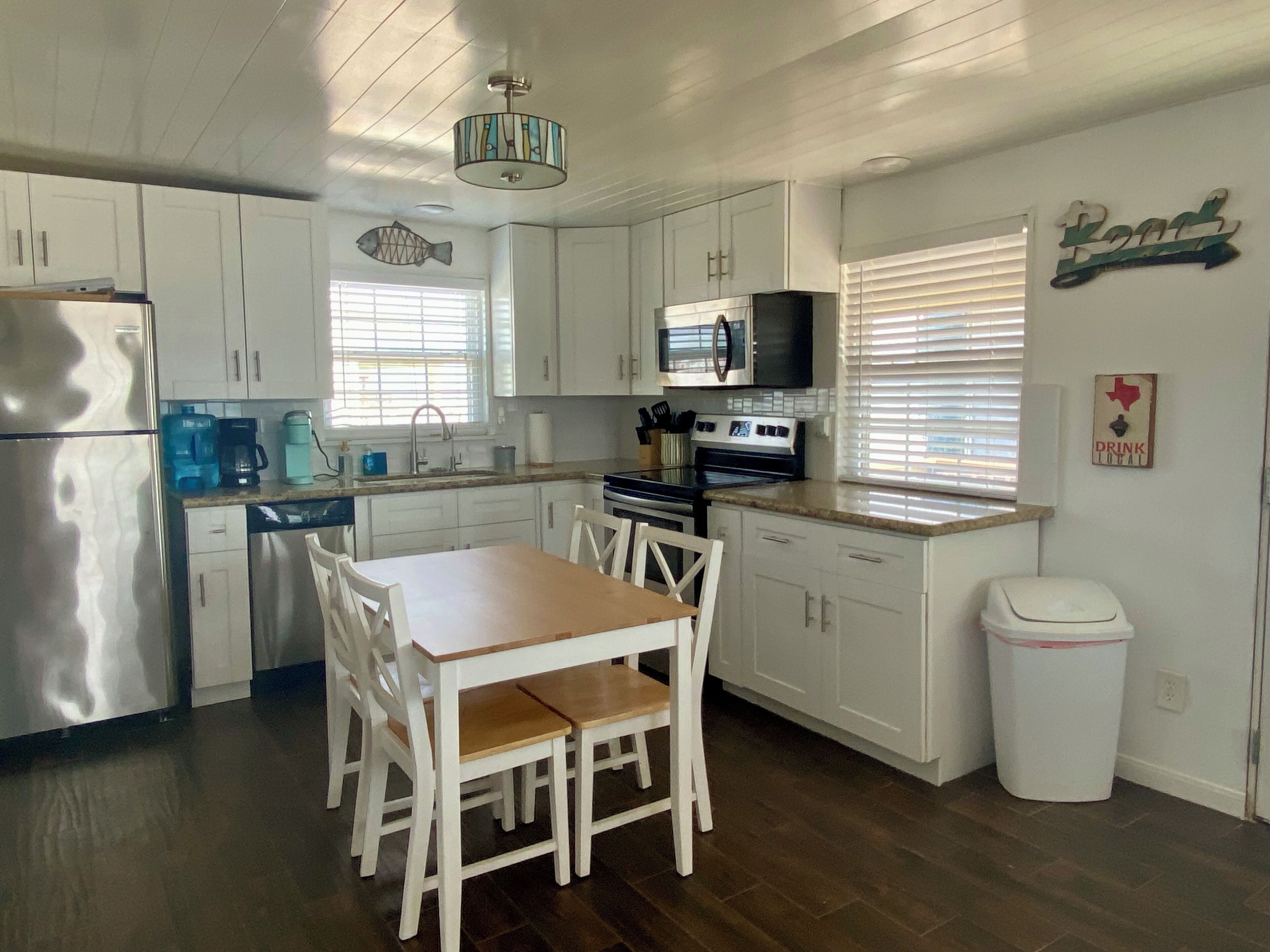 A kitchen with white cabinets, a wooden dining table, and a stainless steel refrigerator.