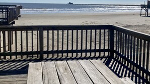 Un pontile in legno con ringhiera che si affaccia su una spiaggia.