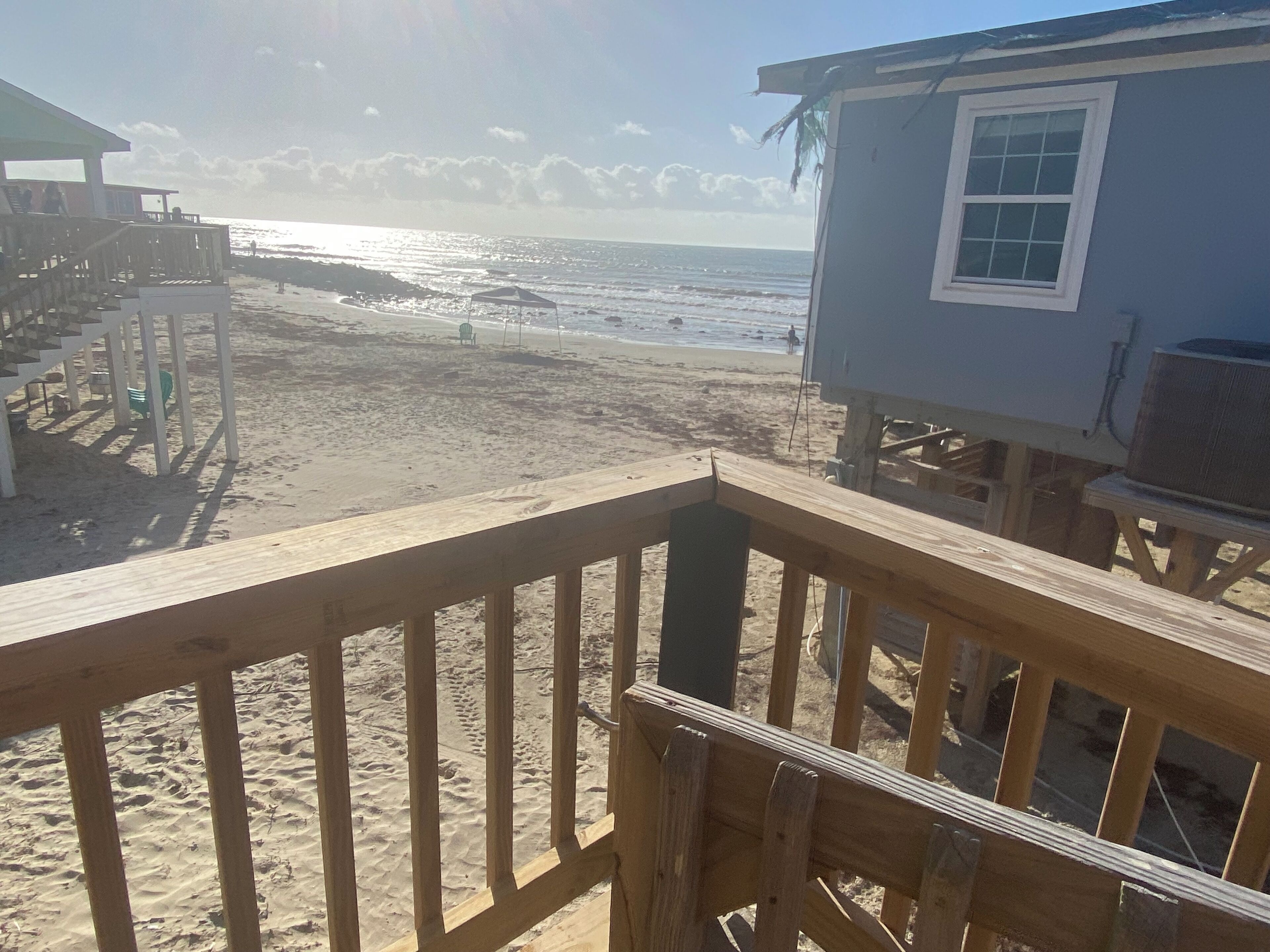 A beach view with a wooden deck, a lifeguard tower, and a building with a window.