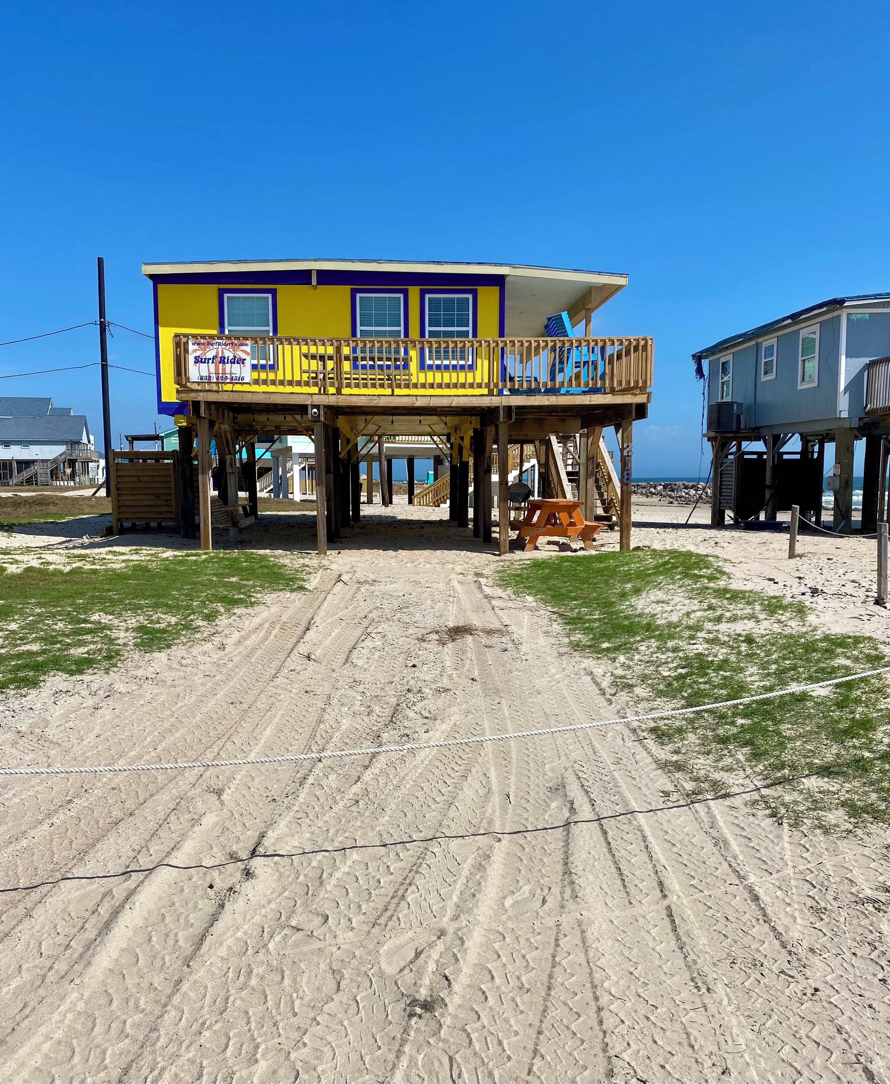 Een strandhuis met een houten terras en een uitkijktoren voor de strandwacht.
