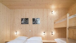 A wooden cabin room with bunk beds, two wall-mounted lights, and two framed pictures. - Amazing Chalet With Whirlpool (Sankt Georgen am Kreischberg)