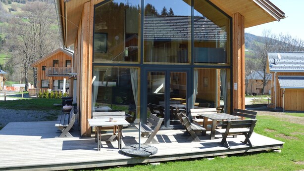 A modern wooden cabin with large glass windows, outdoor seating, and a deck. - Amazing Chalet With Whirlpool (Sankt Georgen am Kreischberg)