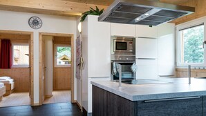 A modern kitchen with a central island, stainless steel appliances, and wooden ceiling beams. - Amazing Chalet With Whirlpool (Sankt Georgen am Kreischberg)