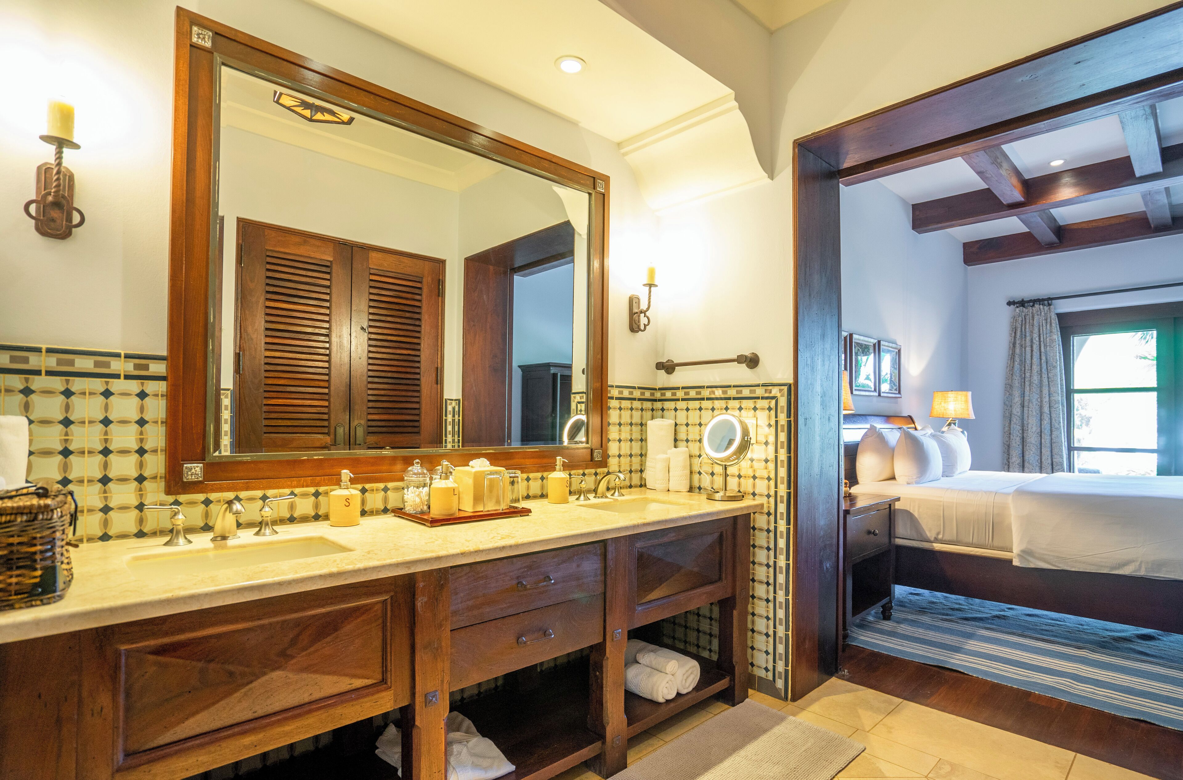 A bathroom with a double sink, wooden vanity, and a large mirror.