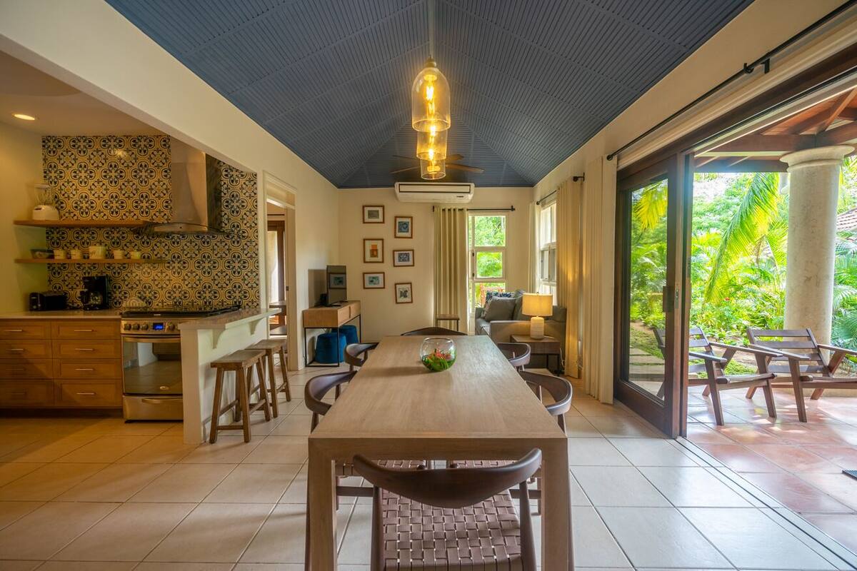 A spacious kitchen with a wooden dining table, chairs, and a ceiling fan.