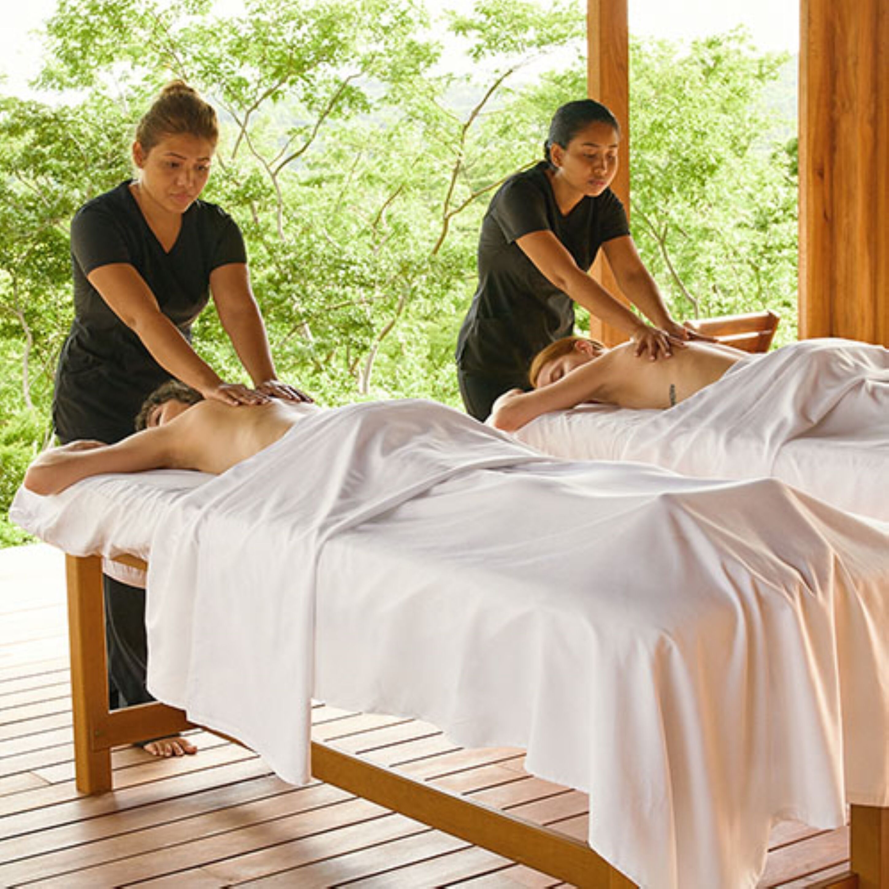 Une séance de massage dans une pièce en bois, avec un plancher en bois et une vue sur des arbres verdoyants.