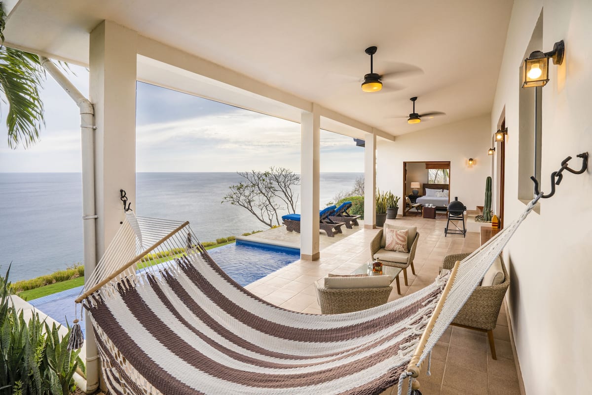 A spacious outdoor area with a hammock, seating, and a view of the ocean.