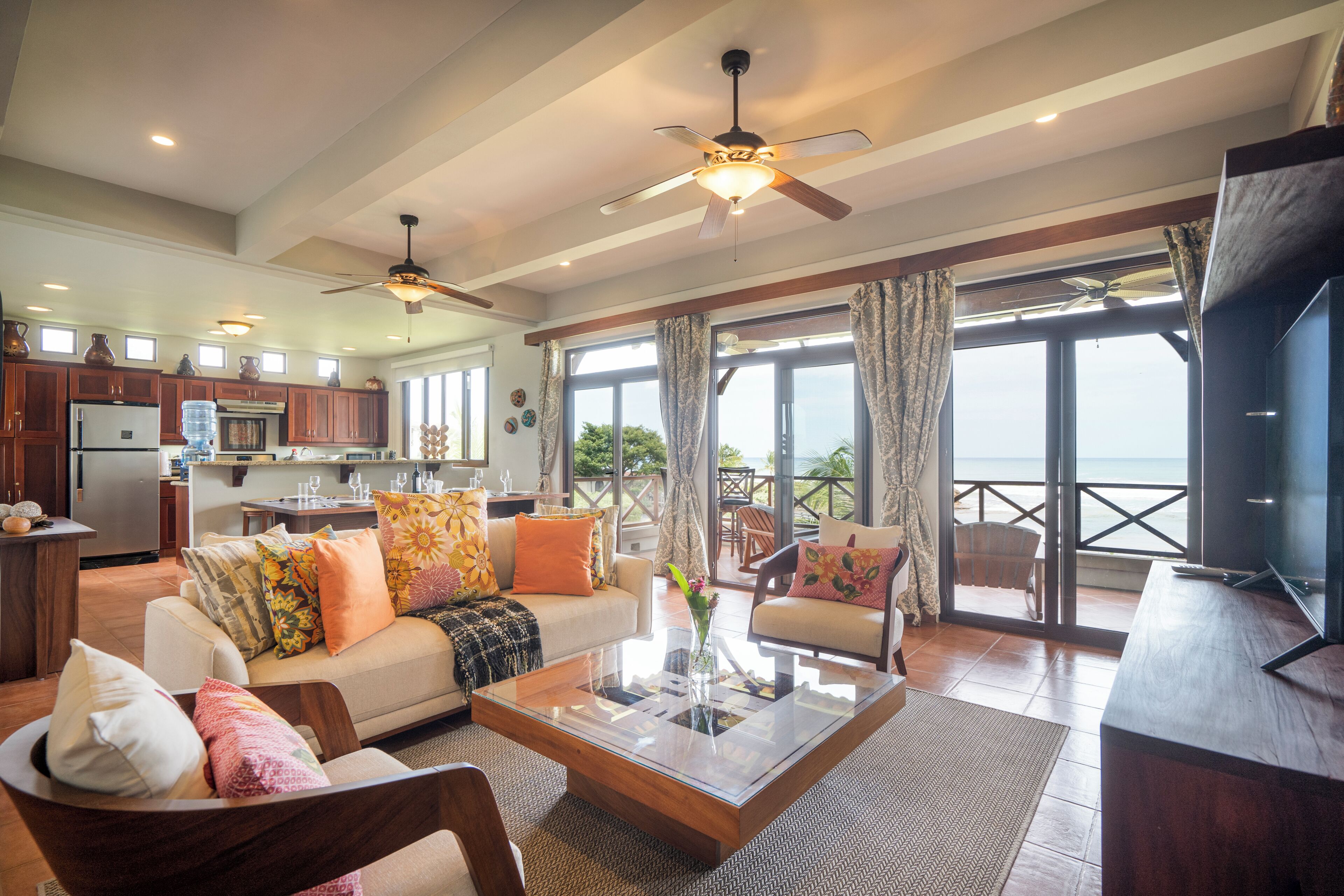 Amplia sala de estar con un televisor grande, asientos cómodos, una cocina y un balcón con vistas.