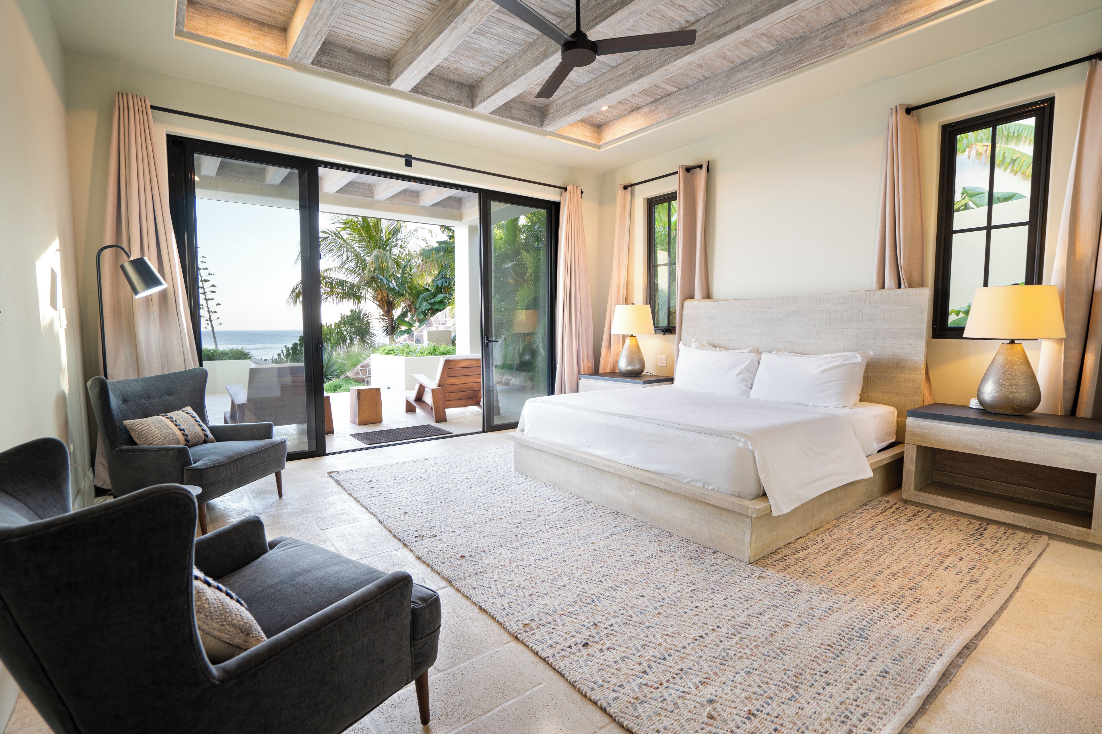 Un dormitorio con una cama grande, un escritorio, una silla y vistas al exterior.