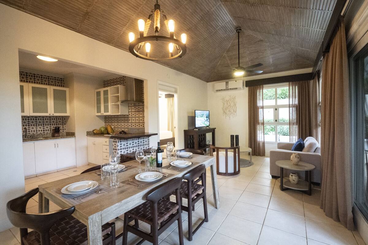 A spacious kitchen with a dining area, wooden ceiling, and a television.