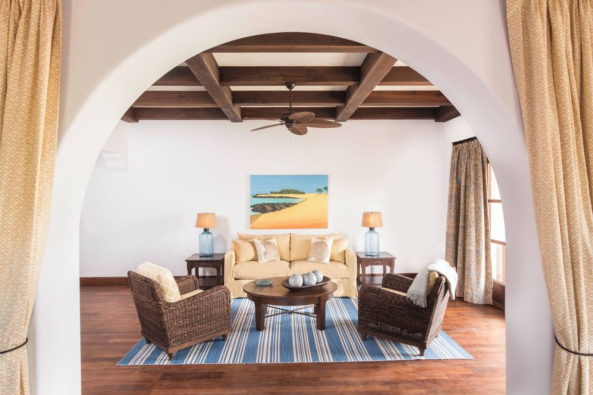 A cozy living room with a sofa, two armchairs, a coffee table, and a ceiling fan.