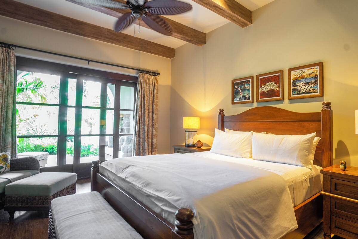 A hotel room with a large bed, a desk, a chair, and a window with curtains.