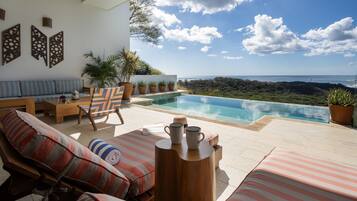 Un espace aménagé au bord de la piscine, avec des chaises longues, une table en bois et des plantes en pot.