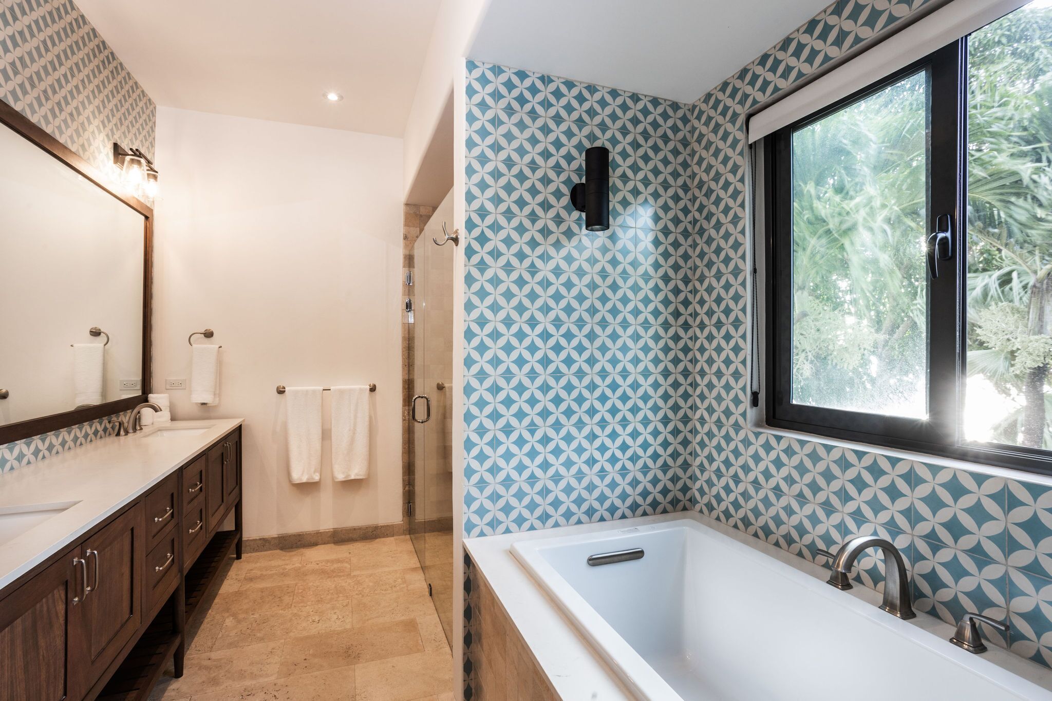 A modern bathroom with a large bathtub, a walk-in shower, and a vanity with a mirror and towel rack.
