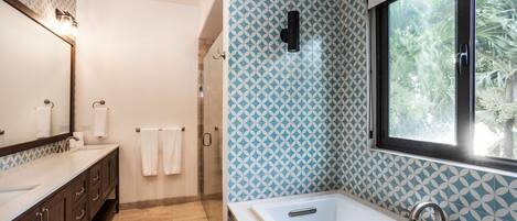 Une salle de bain moderne dotée d’une grande baignoire, d’une douche à l’italienne et d’un meuble-lavabo avec un miroir et un porte-serviettes.