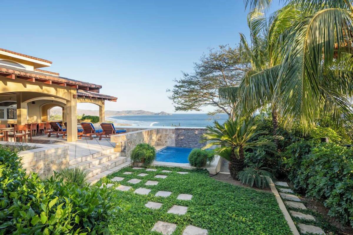 A patio with outdoor seating, a swimming pool, and a view of the ocean.